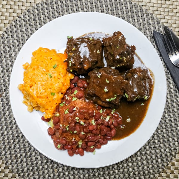 Ruthies Caribbean Kitchen oxtail with rice and peas, and mac and cheese on a white plate.