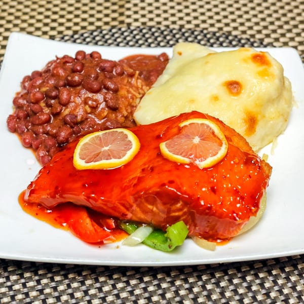 Ruthies Caribbean Kitchen's salmon with red sauce and lemon slices, served with rice and beans, and mashed potatoes.